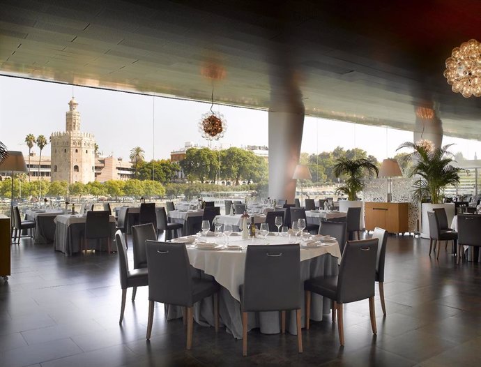 Panorámica interior de una de las salas del restaurante de Abades Triana de Sevilla con vistas a la Torre del Oro