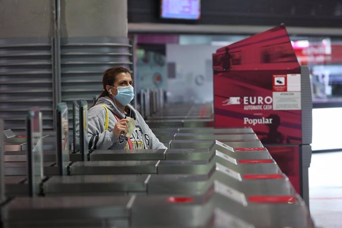 Una viajera con mascarilla atraviesa un torno en la estación de Atocha