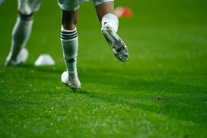 Un jugador con botas y medias de fútbol juega en un campo.