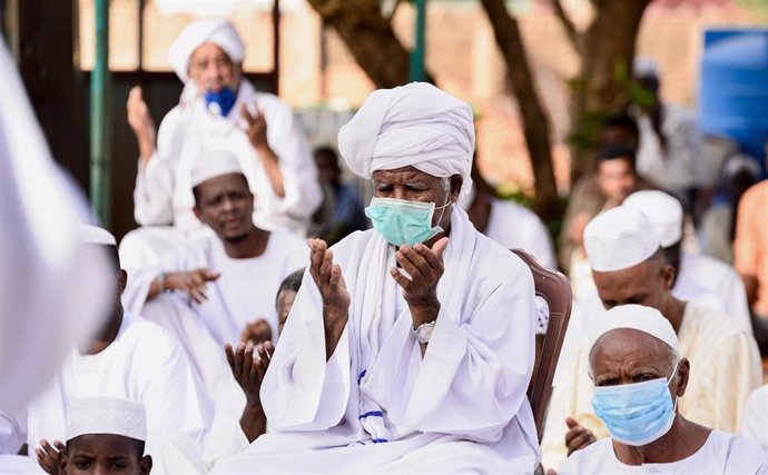 Hombres con mascarillas rezando en Sudán