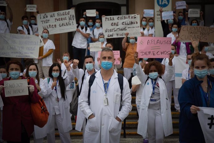 Decenas de miembros del personal sanitario protegidos con mascarilla sostienen carteles durante la concentración de sanitarios en el Día Internacional de la Enfermería a las puertas del Hospital Vall d'Hebron, en Barcelona, a 12 de mayo de 2020.