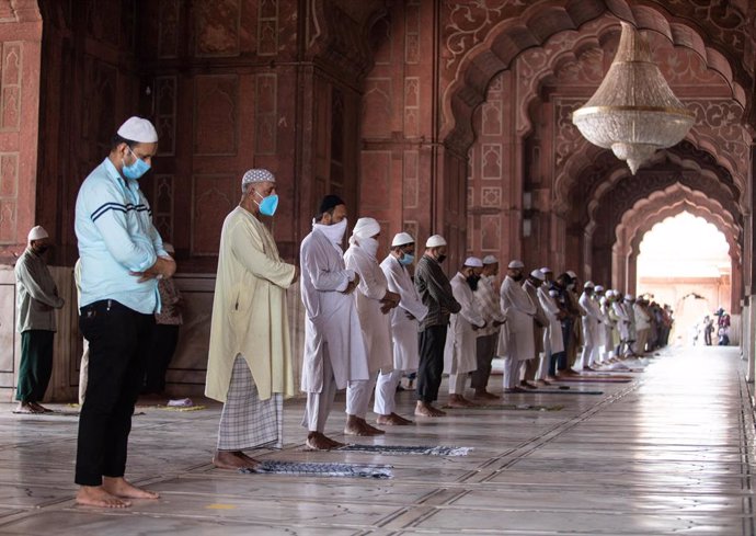 Musulmanes indios rezando con mascarilla y guardando la distancia en una mezquieta de Nueva Delhi