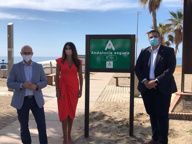 La delegada de Turismo, Nuria Rodriguez, junto al distintivo Andalucía Segura en una playa de Mijas, junto al alcalde, Josele González, a la derecha de la imagen.