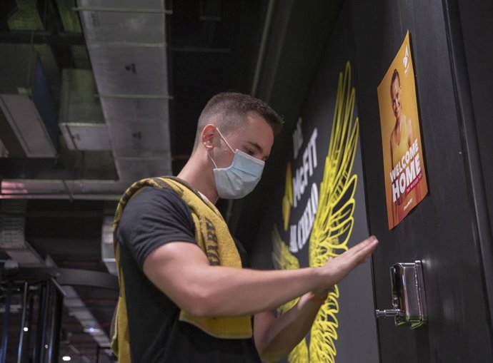 Una persona con mascarilla se lava las manos con hidrogel