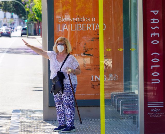 Una señora parando el autobús   en el  primer día del uso obligatorio de mascarillas por el Covid-19. Sevilla a 21 de mayo del 2020