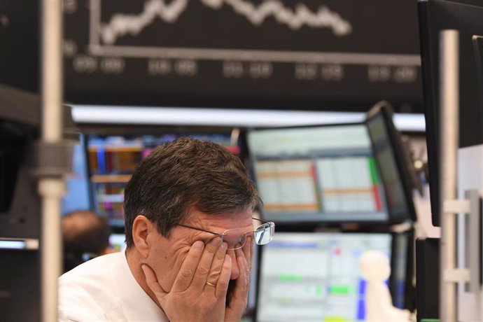 09 March 2020, Hessen, Frankfurt/Main: A stock trader rubs his eyes on the floor of the Frankfurt Stock Exchange. Stock exchanges around the world are reacting with huge losses to the fall in oil prices and concerns about the economic consequences of th