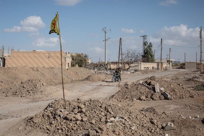 Ruinas en la región de Raqqa y una bandera de las Unidades de Protección Popular kurdo-sirias (YPG)