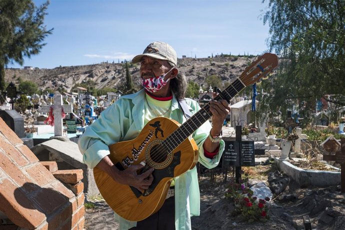Un hombre toca su guiterra durante la ceremonía de un entierro por una víctima de la COVID-19 en la ciudad de Chalco, en Estado de México, una de las regiones más afectadas por la pandemia.