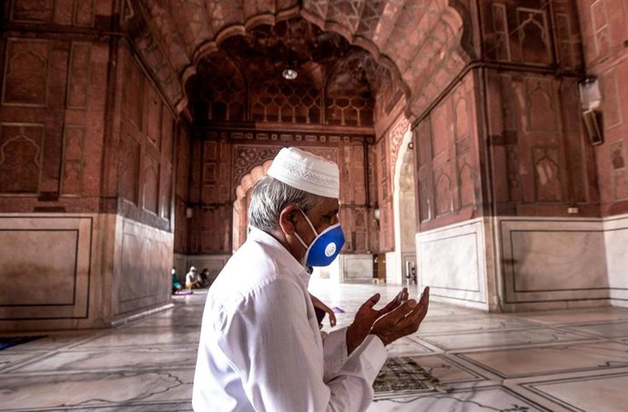 Un hombre con mascarilla reza en Nueva Delhi