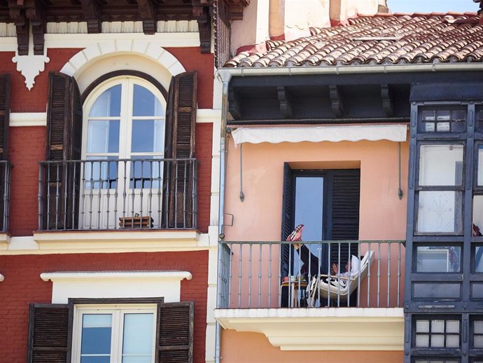 Un joven con su teléfono móvil en el balcón de su casa en Pamplona