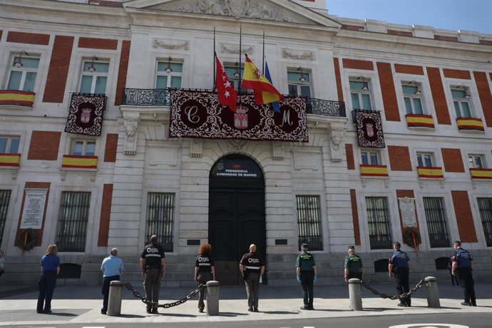 Miembros de distintos cuerpos de seguridad, como la Guardia Civil y la Policía Municipal de Madrid, guardan un minuto de silencio en memoria por los fallecidos por el COVID-19 en la Puerta de Sol, sede del Gobierno regional.