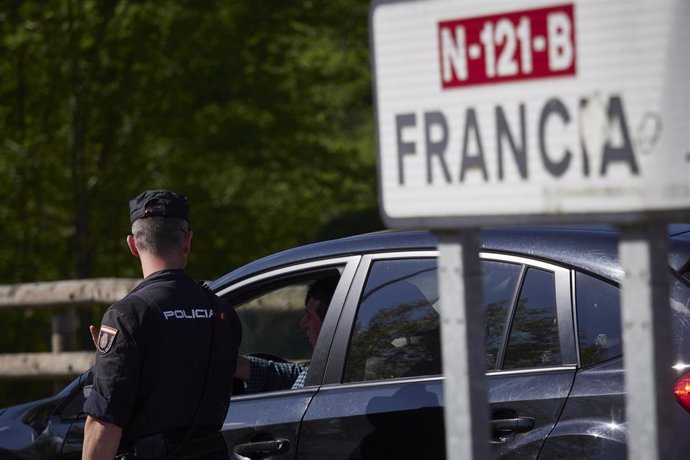 Un cartel señala la dirección a Francia mientras un policía interroga a un conductor en un control en la frontera navarro-francesa.