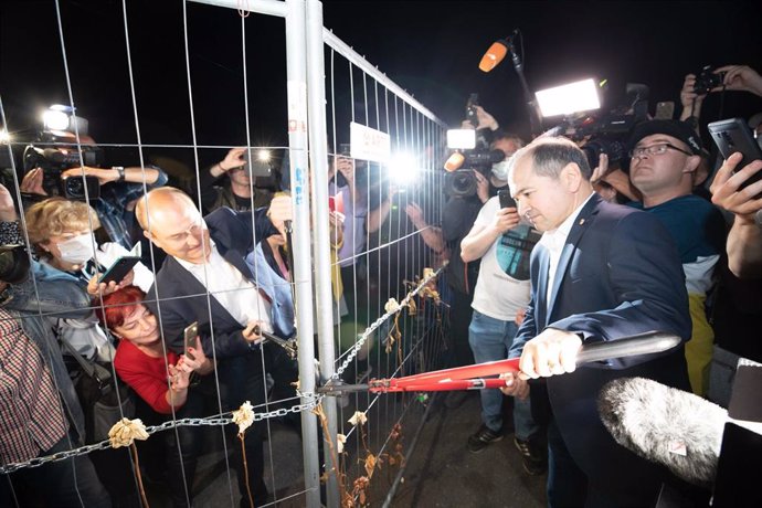 12 June 2020, Saxony, Goerlitz: Octavian Ursu (R), Lord Mayor of Goerlitz in Germany, and Rafal Gronicz (L), Mayor of Zgorzelec in Poland, together open the border fence on the Goerlitz Old Town Bridge. After almost three months, Poland has reopened its