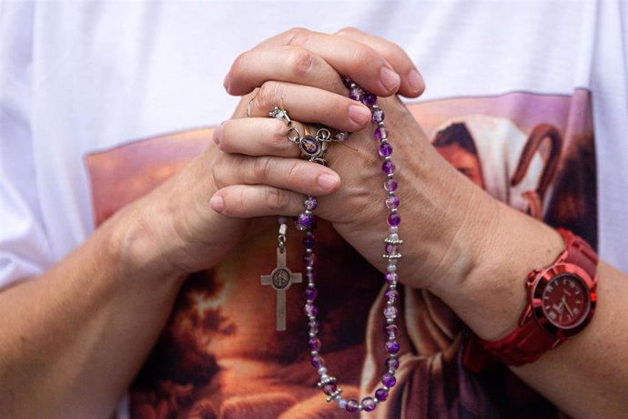 Persona rezando con un rosario