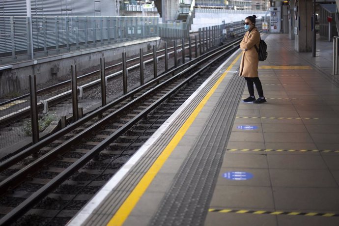 Una dona amb mascarilla espera en una andana d'una estació de Londres.