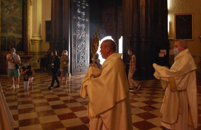 El obispo de Málaga, Jesús Catalá, porta el Santísimo por el interior de la Catedral de Málaga, donde se ha celebrado marcado por las restricciones del COVID-19