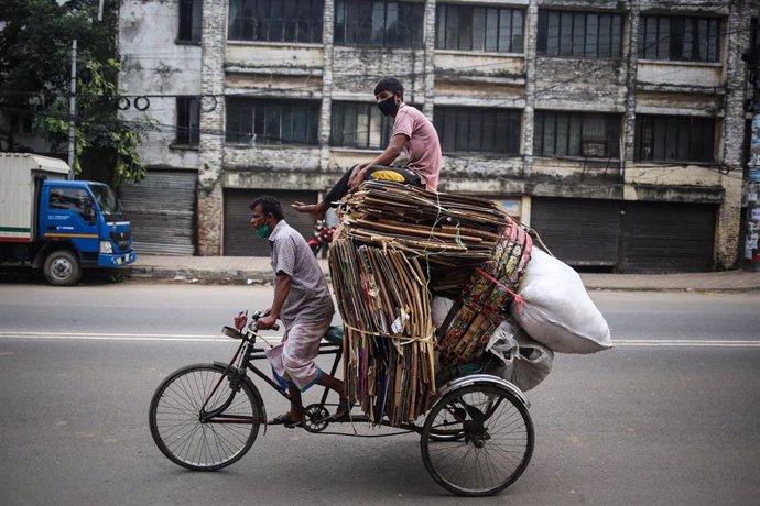 Cartoneros con mascarilla en una bicicleta en Dacca, Bangladesh