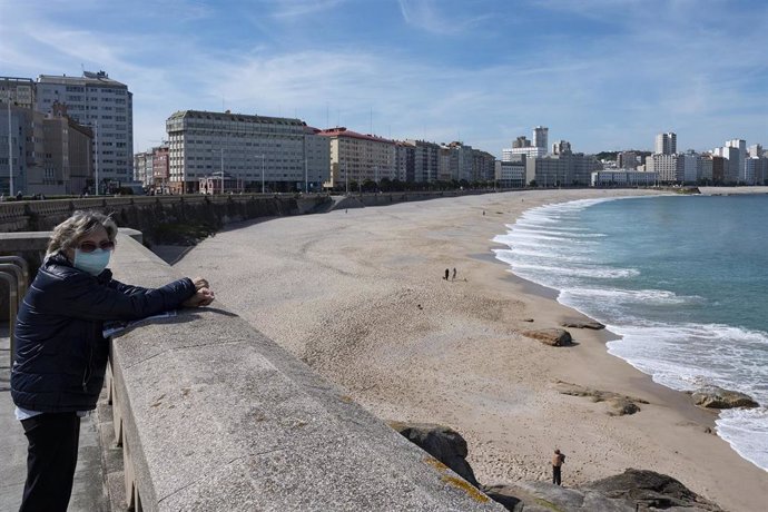 Una mujer en el paseo marítimo de A Coruña (Galicia) con la playa del Orzán de fondo, en el segundo día en que el Gobierno permite salir a hacer deporte de forma individual y pasear con otra persona con la que se conviva, a determinadas horas, según la 