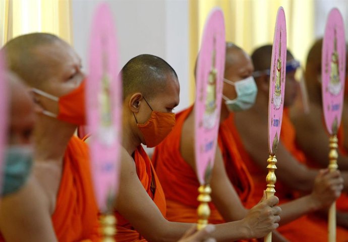 Un grupo de monjes ataviados con mascarillas ora en un templo de la ciudad de Bangkok, la capital de Tailandia.