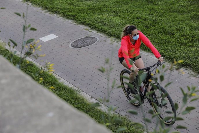 Una mujer en bicicleta en el antiguo cauce del río Turia en el primer día de salida en Valncia