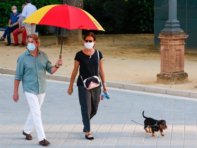 Una pareja con un paraguas con la bandera española de dirige a una nueva concentración celebrada en el Parque de María Luisa, contra el Gobierno central por su gestión ante la pandemia de coronavirus Covid-19. Sevilla a 20 de mayo de 2020