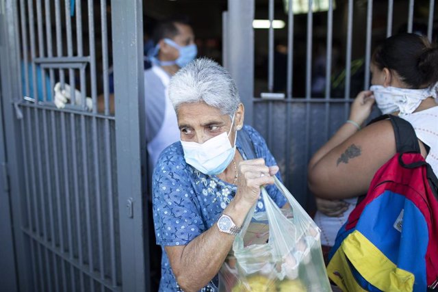 Una mujer con mascarilla y una bolsa de la compra en Caracas