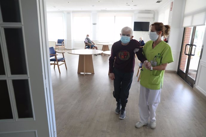 Una treballadora d'un asil ajuda a caminar a un resident durant el primer dia de visites en la Residncia Centro Casaverde Navalcarnero des que es va tancar pel coronavirus. En Navalcarnero, Madrid (Espanya), a 8 de juny de 2020.