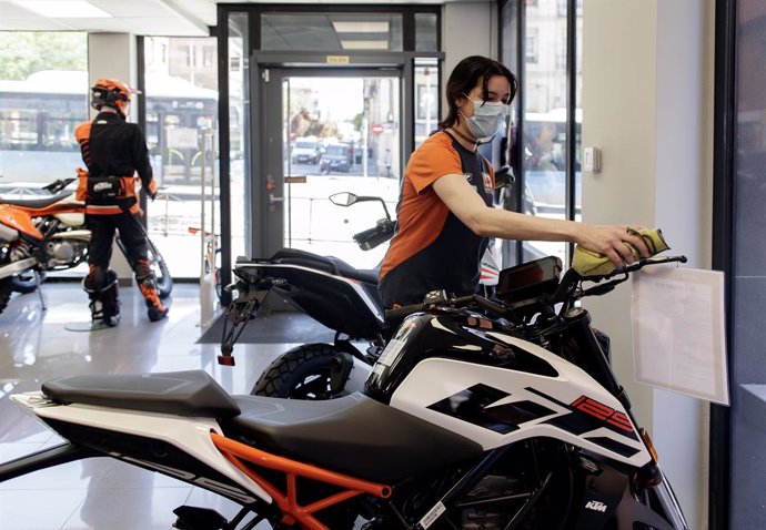 Una trabajadora limpia el interior del concesionario de motocicletas.