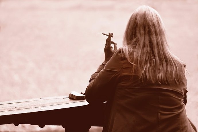 Mujer fumadora mirando al lago