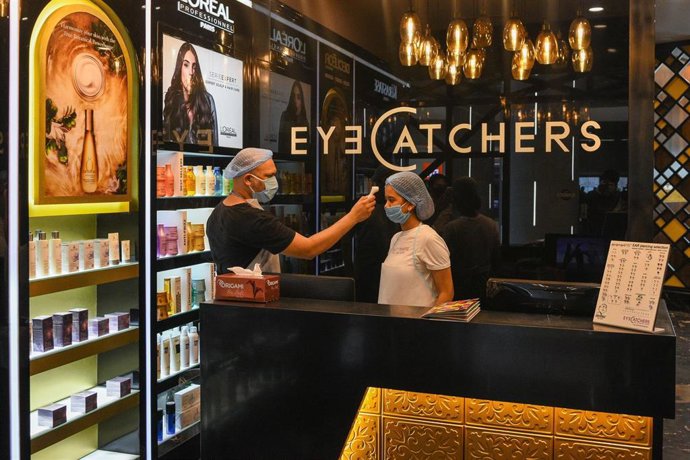 Toma de temperatura a una empleada de un centro de belleza en Calcuta