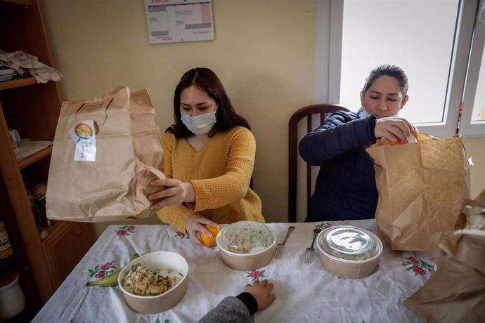 Dos mujeres durante la comida en su casa del barrio madrileño de Carabanchel abren el menú de la ONG del chef José Andrés