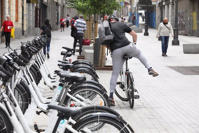 Un hombre coge una bicicleta de bicimad aparcada en una calle de la capital