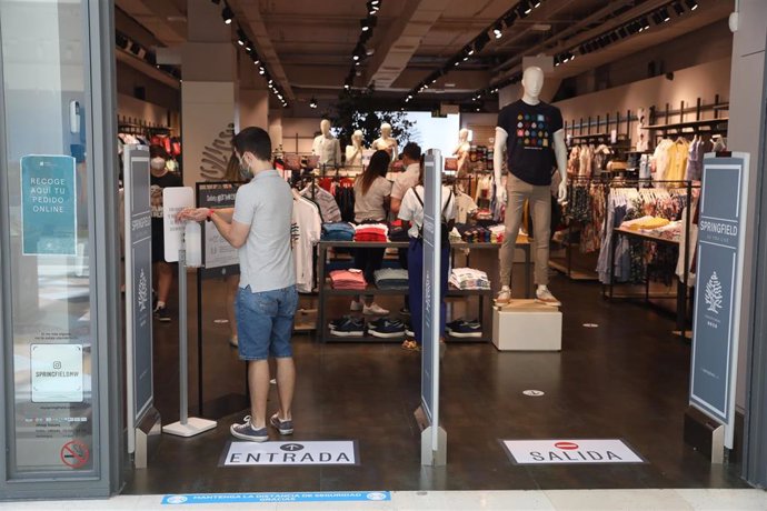 Un joven utiliza un dispensador de gel hidroalcohólico a su entrada en una tienda del Centro Plaza Norte 2.  