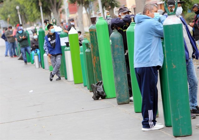 Una fila de personas esperando para poder rellenar sus balones de oxígeno en una calle de Lima, Perú.