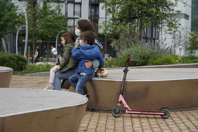 Una mujer sentada junto a una niña y un niño en un parque de Bilbao