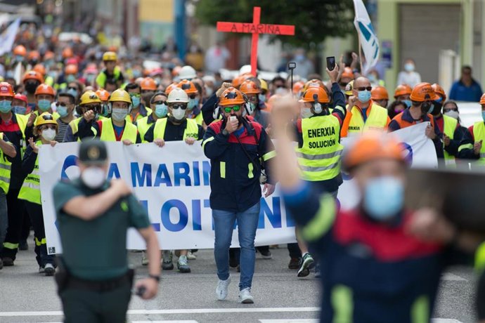 Trabajadores de Alcoa caminan por la calle con una pancarta