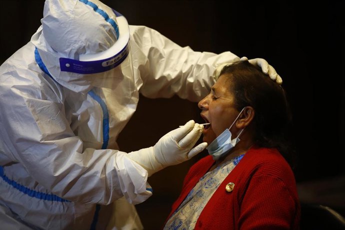 07 May 2020, Nepal, Kathmandu: A health worker takes a throat swab sample for the coronavirus PCR test from a woman, as the government is testing the members of National Assembly and House of Representatives for the novel coronavirus a day before the ne