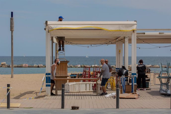 Diversos treballadors preparen la terrassa d'un bar al costat de la platja durant el segon dia de la reobertura al públic de les terrasses a l'aire lliure, a Barcelona, Catalunya (Espanya) a 26 de maig de 2020.