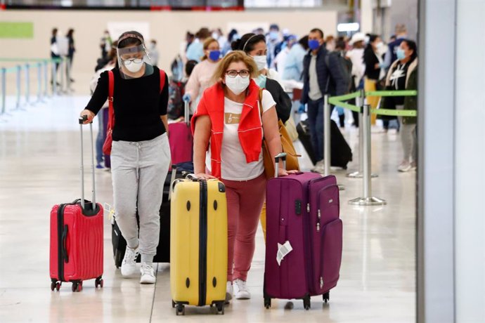 Varios pasajeros protegidos con mascarilla pasan los controles en la terminal 4 del Aeropuerto de Madrid-Barajas Adolfo Suárez.  En Madrid (España), a 17 de mayo de 2020.