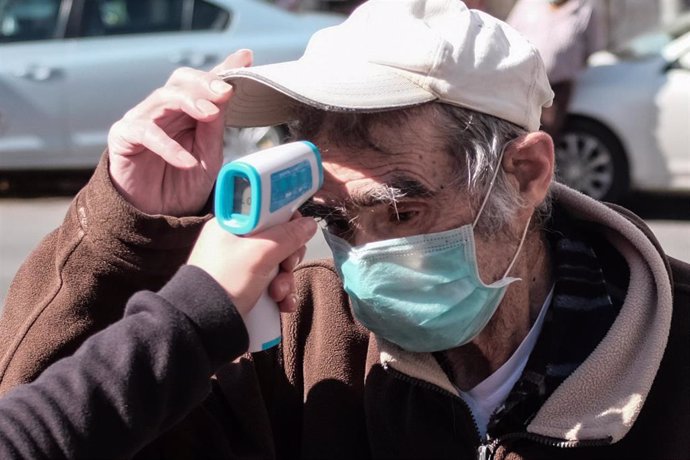 Toma de temperatura a un hombre antes de entrar a un mercado en Jerusalén durante la pandemia de coronavirus
