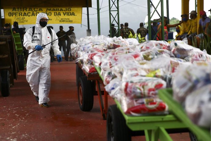 Un soldado brasileño desinfecta las bolsas de ayuda humanitaria que llegaron al municipio paraense de Afua, en el norte de Brasil, para paliar los estragos de la pandemia de la COVID-19.