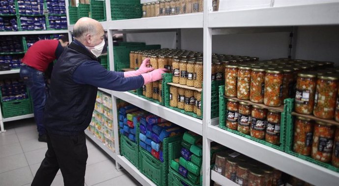Un voluntario de la fundación FAYEC protegido con mascarilla coloca productos en el Banco de Alimentos de Madrid.