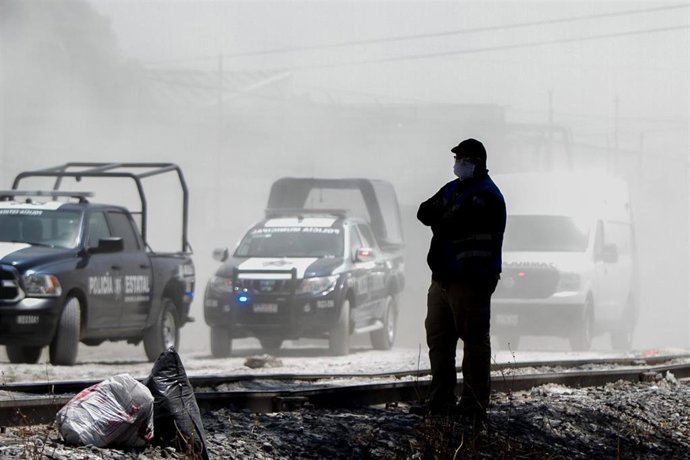 Un hombre observa el paso de vehículos policiales en México