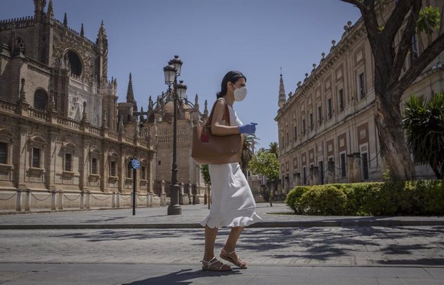 Una mujer con mascarilla y guantes caminando por la Av. de la Constitución durante el quinto día de la fase 2 en Sevilla (Andalucía, España), a 29 de mayo de 2020.