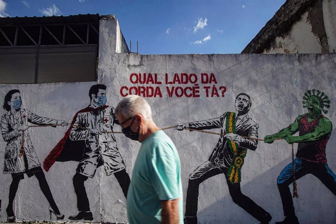Un hombre pasa por delante de un mural que critica la gestión del presidente de Brasil, Jair Bolsonaro, durante la gestión de la pandemia, en Sao Paulo.