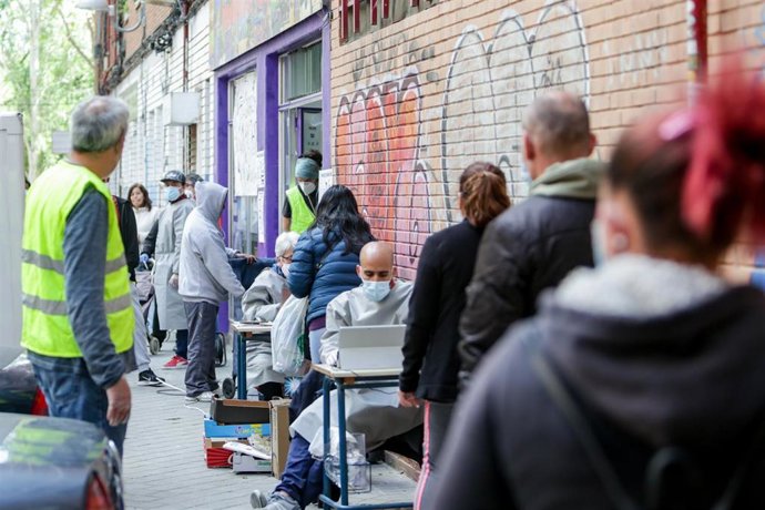 Vecinos realizan una cola para recoger bolsas de la Asociación de Vecinos Parque Aluche donde los voluntarios han entregado alimentos y productos donados en su sede ubicada en la calle Quero n 69 a aquellas personas que lo necesitan. En Aluche, Madrid.