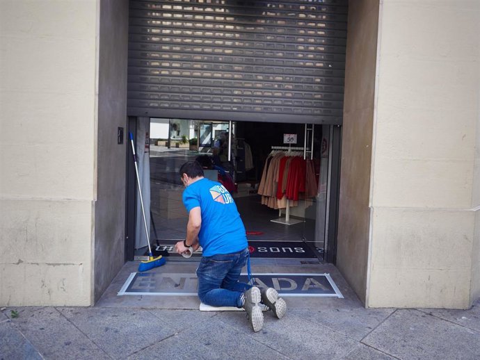 Un trabajador de las tiendas de moda "Urban" de Pamplona prepara el establecimiento para su reapertura durante el estado de alarma por el coronavirus.