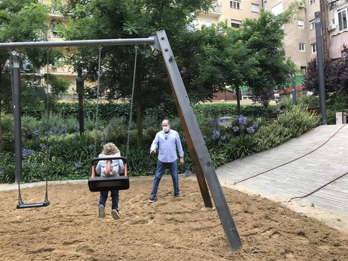 Una niña y su abuelo juegan en los columpios en el interior de la manzana Montserrat Figueras en el día de la reapertura de las zonas de juego