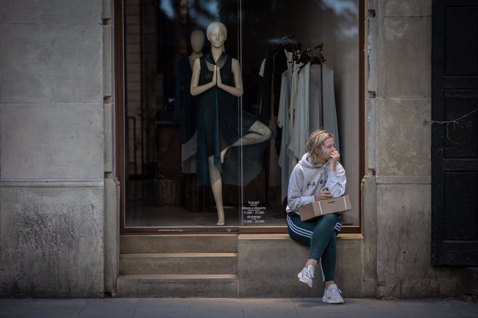 Una dona espera al fet que obri una botiga de roba, durant el segon dia de la Fase 1 a Barcelona en la qual es permet reobertura de locals i establiments minoristes, Catalunya (Espanya) a 26 de maig de 2020.