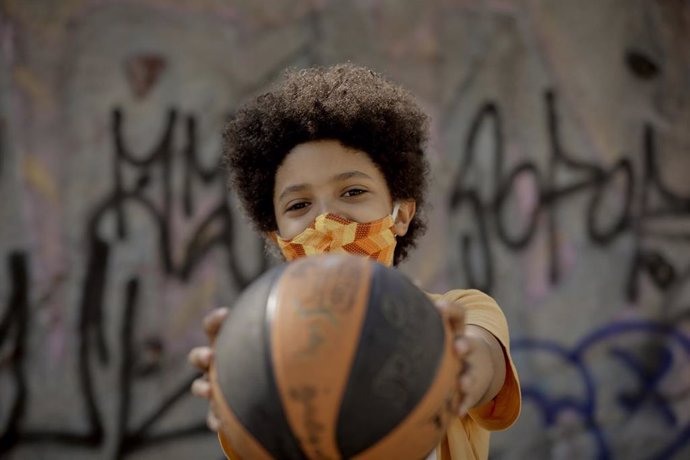 El niño actor y modelo Hugo Ndiaye, de 10 años, juega al baloncesto en un parque. En Madrid (España) a 28 de mayo de 2020.